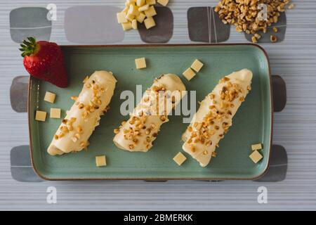 Barre meringa ricoperte di cioccolato bianco con noci in cima adagiate su un piatto blu Foto Stock