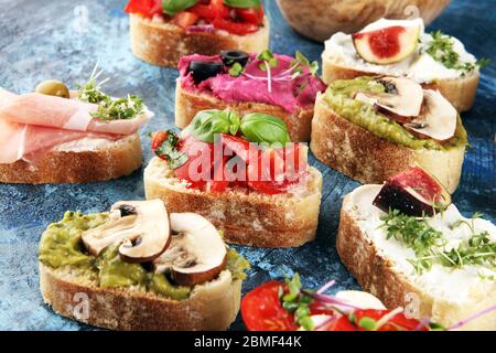 Bruschette assortite con vari condimenti. Bruschetta appetitosa o crostini crudo. Varietà di piccoli panini. Mescolare la bruschetta Foto Stock