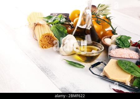 Il cibo italiano ha origine con erbe e spezie, pomodori di vite, basilico, spaghetti, olive, parmigiano, olio d'oliva, aglio, pepe e rosmarino Foto Stock