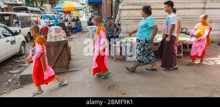 Yangon Myanmar - Ottobre 26 2013; viaggio e le immagini della gente tre monaci principianti ragazzi camminare sulla strada della città con le loro ciotole di elemosina. Foto Stock