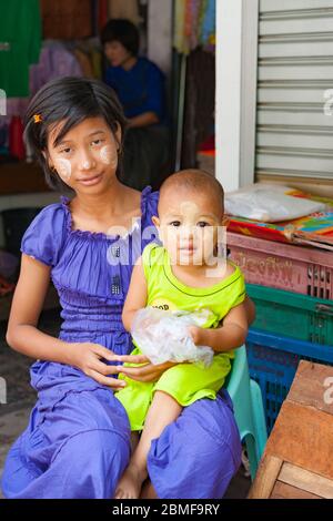 Yangon Myanmar - Ottobre 26 2013; Myanmar immagini di viaggio la ragazza teenage e la sua sorella piccola entrambi con thanaka tradizionale sui loro volti seduti in str Foto Stock