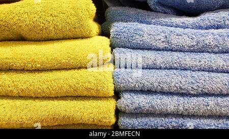 Pile di soffici asciugamani da bagno di vari colori in una finestra del negozio. Asciugamani di cotone Terry in una pila sugli scaffali di un supermercato Foto Stock