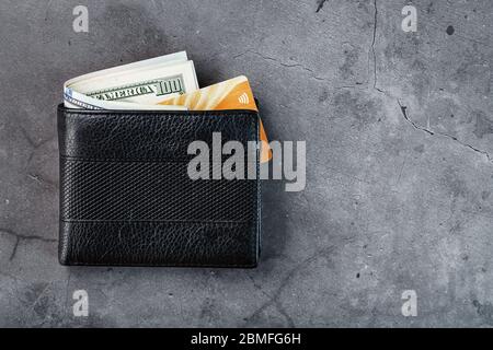 Un portafoglio nero con banconote e una carta elettronica d'oro su fondo grigio scuro. Simbolo di prosperità e prosperità. Spazio libero, vista dall'alto Foto Stock