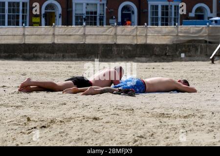 Weymouth, Dorset, Regno Unito. 9 maggio 2020. UK Weather: Due uomini che prendono il sole sulla spiaggia in una giornata di sole caldo bruciante presso la località balneare di Weymouth a Dorset durante il blocco del coronavirus. Credito immagine: Graham Hunt/Alamy Live News Foto Stock