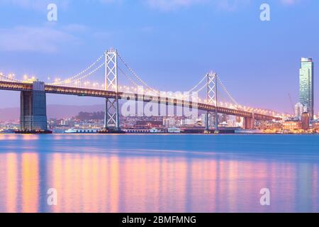 Una vista illuminata san francisco-oakland Bay Bridge all'alba, San Francisco, California, Stati Uniti Foto Stock