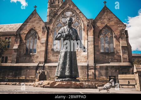Una grande statua in pietra e un piccione di fronte ad una chiesa. Foto di alta qualità Foto Stock