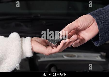 Meccanico che consegna le chiavi dell'auto al cliente dopo la manutenzione Foto Stock