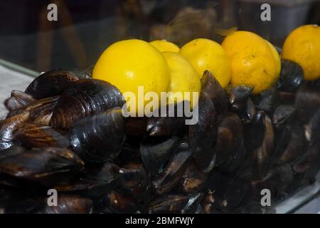 Cozze bollite in ciotola di ceramica guarnite con erbe fresche e limone. Gustoso pasto a base di pesce ideale per pranzo o cena, antipasto per brunch o buffet Foto Stock