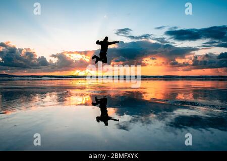 Silhouette di una persona che salta alla spiaggia di Westward ho, Devon Foto Stock