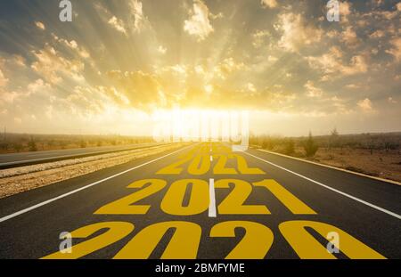 La parola 2021 scritta sulla strada statale nel mezzo di strada asfaltata vuota all'alba dorata Foto Stock