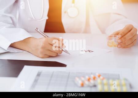 Donna-medico sconosciuto riempie in su la forma di prescrizione in stanza soleggiata, primo piano Foto Stock