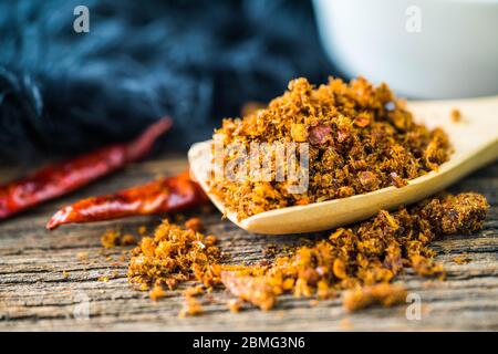 Pasta di peperoncino piccante e secca con cucchiaio di legno e fondo Foto Stock