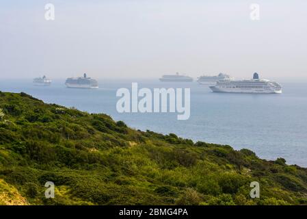 Weymouth, Dorset, Regno Unito. 9 maggio 2020. UK Weather: Cinque navi da crociera ancorate nella baia al largo della costa della località balneare di Weymouth a Dorset in una calda giornata di sole a causa della chiusura dell'industria di crociera durante il blocco dei coronavirus. Ci sono quattro navi P&o che sono Oceana, Aurora, Arcadia e Ventura e una nave Cunard la nave Liner Queen Mary 2. Credito immagine: Graham Hunt/Alamy Live News Foto Stock