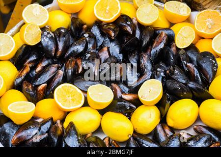 Cozze bollite in ciotola di ceramica guarnite con erbe fresche e limone. Gustoso pasto a base di pesce ideale per pranzo o cena, antipasto per brunch o buffet Foto Stock