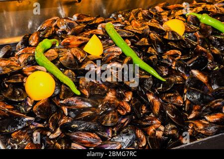 Cozze bollite in ciotola di ceramica guarnite con erbe fresche e limone. Gustoso pasto a base di pesce ideale per pranzo o cena, antipasto per brunch o buffet Foto Stock