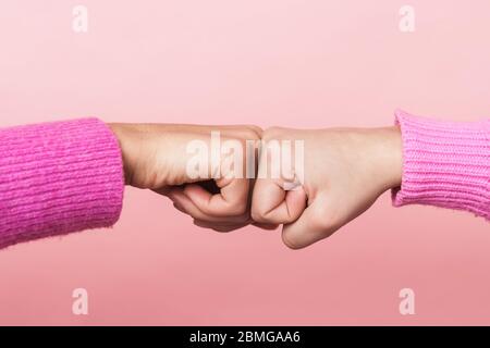 Immagine primo piano di due ragazze adolescenti che urtare i loro pugni insieme in conciliazione o amicizia isolato su sfondo rosa Foto Stock