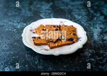 Fette di torta di OAT cruda biologica a forma quadrata con scaglie di banana e cioccolato. Dessert biologico. Foto Stock