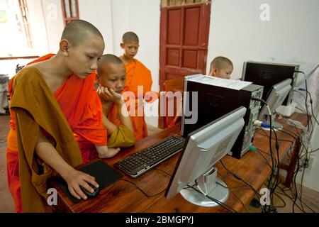 GIOVANI BUDDISTI MONACI CHE USANO COMPUTER A LUANG PRABANG, LAOS Foto Stock