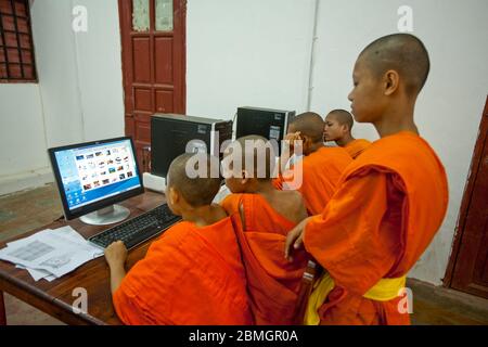 GIOVANI BUDDISTI MONACI CHE USANO COMPUTER A LUANG PRABANG, LAOS Foto Stock