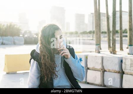 Giovane adolescente si siede mentre lei fuma Foto Stock