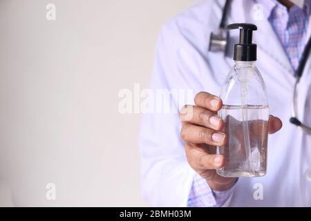 medico con maschera facciale che mostra igienizzante per le mani Foto Stock
