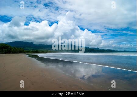 Spiaggia curva sotto le montagne Foto Stock