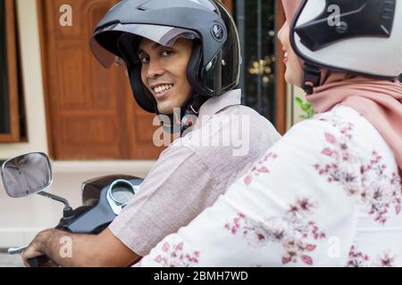 donna musulmana e uomo che cavalcano insieme moto Foto Stock