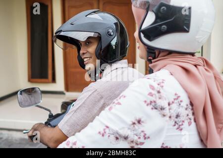 donna musulmana e uomo che cavalcano insieme moto Foto Stock