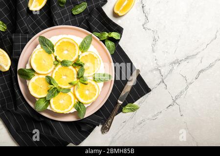 Piatto con delizioso cheesecake e limoni sul tavolo Foto Stock