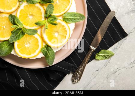 Piatto con delizioso cheesecake e limoni sul tavolo Foto Stock