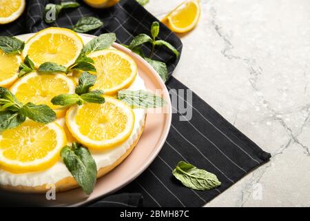 Piatto con delizioso cheesecake e limoni sul tavolo Foto Stock