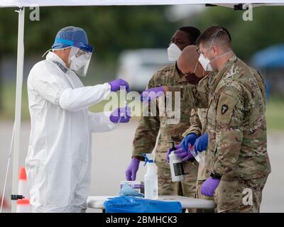 SPC. Nicholas Cisneros consegna un tampone nasale preso da un paziente mentre il team di prova mobile della guardia del Texas (MTT) prova per il coronavirus ad una clinica libera di drive-up nella piccola città centrale del Texas di Taylor. Foto Stock