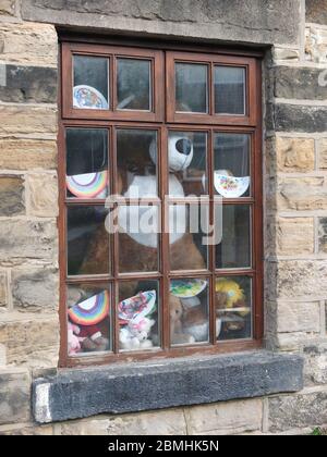 Orsacchiotti, giocattoli coccolati e piatti di carta dipinti con motivi arcobaleno in una finestra cottage a Sheffield durante il blocco di Coronavirus Foto Stock