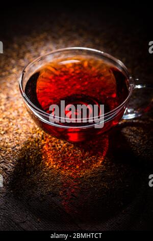 Tazza di delizioso tè rooibos su sfondo scuro Foto Stock