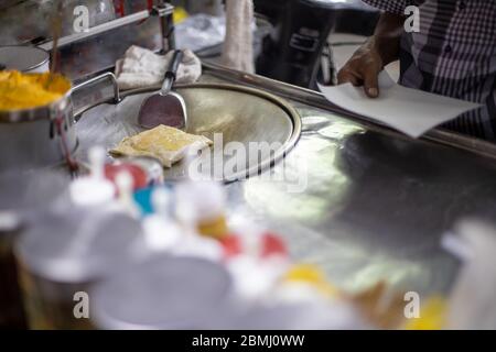 Processo per la preparazione di gustosi pancake tradizionali tailandesi su un bancone. Mani maschili friggere una frittella in olio. Specialità locali. Foto Stock
