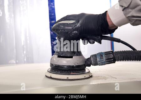 Auto meccanica di lucidatura e lucidatura auto in officina auto riparazione con lucidatrice orbitale, pulizia di base strato Foto Stock