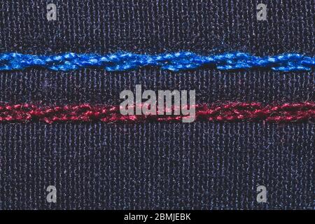 Cucitura blu e rossa su tessuto nero. Punti su materiale tessile primo piano Foto Stock