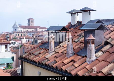 Tetto con camini con vista sfocata su Venezia in una fresca mattina presto, Italia Foto Stock