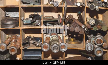 Bulloni e dadi metallici nel ripiano di lavoro. Vari dispositivi di fissaggio. Particolari arrugginiti in officina Foto Stock