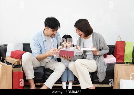 Mamma e papà asiatici stanno disimballando regali con la loro figlia Foto Stock