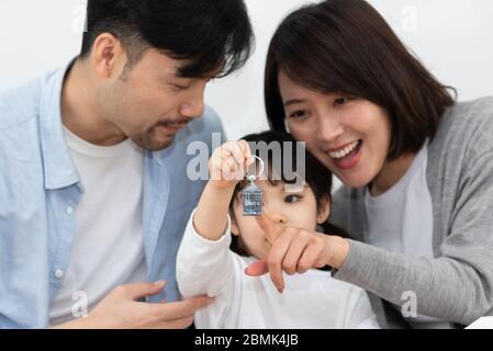 Mamma e papà asiatici stanno disimballando regali con la loro figlia Foto Stock