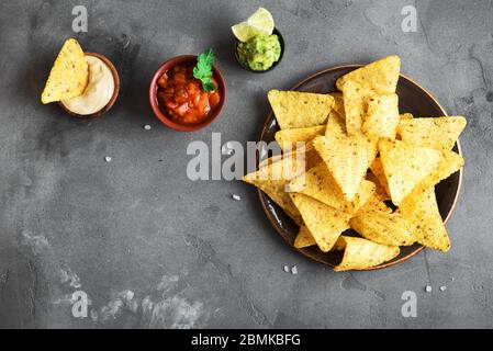 Fiche di mais messicane Nachos e set di tradizionali tuffi, vista dall'alto, spazio per le copie. Tortilla o Nacho chips con salse per lo spuntino. Foto Stock