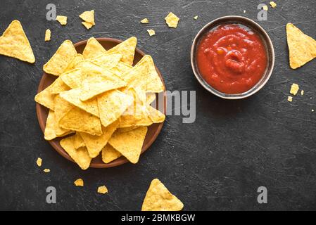 Fiche di mais messicane Nachos e salsa tradizionale tuffarsi in nero, spazio copia. Tortilla o Nacho chips con salsa di pomodoro calda per uno spuntino. Foto Stock