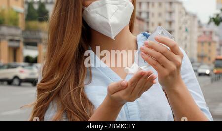 COVID-19 Pandemic Coronavirus Close up Unidentified Woman with KN95 FFP2 Mask using alcohol gel Sanitizer Hands in City Street. Antisettico, igiene an Foto Stock