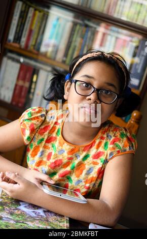 La ragazza indiana piccola studia a casa mantenendo la distanza sociale durante il periodo di blocco per Covid-19. Foto Stock