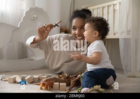 Sorridente madre biraciale che gioca con il bambino piccolo Foto Stock