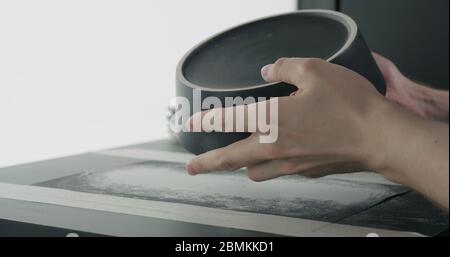 controllare il fondo della ciotola nera in ceramica con le mani dell'uomo Foto Stock