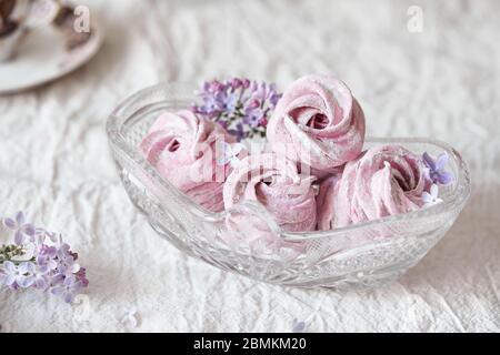 Viola dolce fatto in casa Zephyr o Marshmallow da ribes nero con fiori lilla in vaso di vetro su panno da tavolo bianco Foto Stock