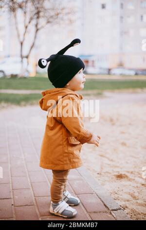 un bambino in un cappello una lumaca con gli occhi sullo sfondo della strada Foto Stock