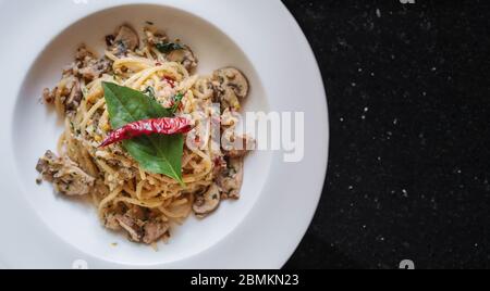 Mescolare gli Spaghetti con pesce salato, spezie tailandesi e peperoncino secco, in un piatto bianco Foto Stock